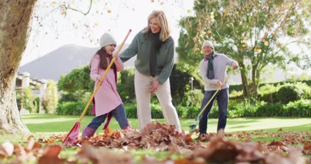Video Happy Caucasian Grandparents Granddaughter Raking Autumn Leaves Sunny Garden — Wideo stockowe