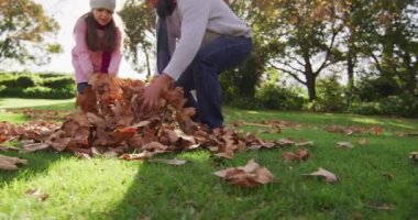 Video of happy caucasian grandfather and granddaughter throwing autumn leaves in sunny garden. Family, domestic life and togetherness concept digitally generated video.