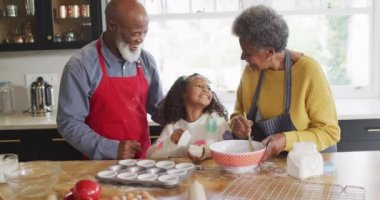 Afrika kökenli mutlu bir Amerikalı torunun büyükannesi ve büyükbabasıyla mutfakta pasta yaptığı video. Aile, aile hayatı ve birliktelik kavramı dijital olarak oluşturulmuş video.