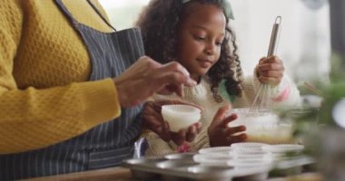 Afro-Amerikan torununun büyükannesiyle mutfakta yemek pişirirken videosu. Aile, aile hayatı ve birliktelik kavramı dijital olarak oluşturulmuş video.