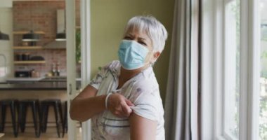 Yüzünde maske olan mutlu son sınıf öğrencisi kadın kollarında yara bandı var. covid 19 salgını sırasında üst düzey sağlık ve yaşam tarzı.