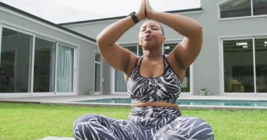 Mutlu Afro-Amerikan artı boyut kadın yoga yapıyor, bahçede meditasyon yapıyor. Sağlıklı yaşam tarzı, evde boş vakitlerin tadını çıkarmak..