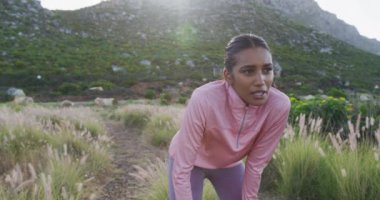 Kırsal kesimde koşarken tarlada dinlenen melez bir kadının portresi. Fitness ve sağlıklı açık hava yaşam tarzı.