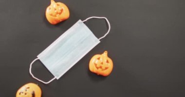 Üç cadılar bayramı balkabağı oyuncağı ve gri arka planda yüz maskesi. Cadılar Bayramı bayramı ve covid-19 pandemik konsepti boyunca kutlama