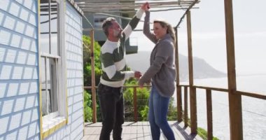 Mutlu Kafkasyalı olgun çift deniz kenarında terasta dans ediyor. Sahildeki evdeki boş vakitlerin tadını çıkarıyorum.