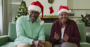 Noel 'de Noel Baba şapkalı mutlu Afrika kökenli Amerikalı çift. Noel, şenlik ve iletişim teknolojisi.