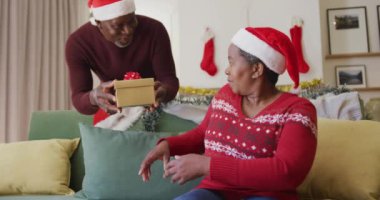 Mutlu kıdemli Afrikalı Amerikalı adam karısına hediye veriyor. Noel kutlamaları, evde kutlama..