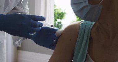 Yüz maskesi takan Afrikalı Amerikalı erkek doktorların evdeki yaşlı kadın hastalara kovid 19 aşısı enjekte etmelerini kapatın. Salgın sırasında korona virüsü tedavisi ve aşı kavramı.