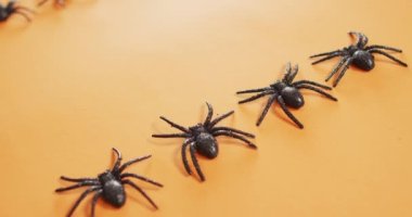 Turuncu arka planda fotokopi alanı olan birden fazla örümcek oyuncağını kapatın. Cadılar Bayramı bayramı ve kutlama konsepti