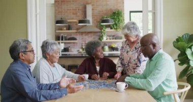 Bir grup mutlu kıdemli arkadaş kahve içip evde yapboz yapıyorlar. Evde arkadaşlarla sosyalleşmek..