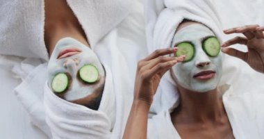 Yüz maskeleri ve salatalıklarla nemlendiren gevşek kadın arkadaş videoları. Arkadaşlık, kendine dikkat etmek ve güzellik kavramı..