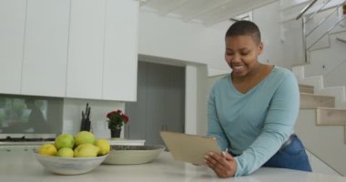 Mutfakta tablet kullanan Afro-Amerikan ve uzun boylu bir kadın. ev hayatı, evde teknolojiyle eğlenmek..