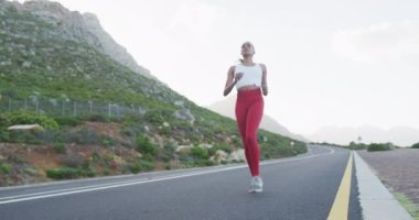 Kırsal yolda koşmaya ara veren melez bir kadın. Fitness ve sağlıklı açık hava yaşam tarzı.