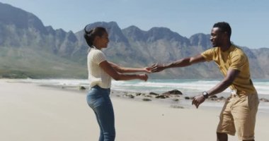 Mutlu Afro-Amerikan çifti sahilde dans ediyor. Doğa keşfi macera turizmi ve sağlıklı yaşam tarzı konsepti