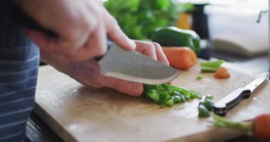 Kesme tahtasında yeşil biber kesen insan ellerine yakın çekim. Evde boş vakitlerin tadını çıkarıyorum..