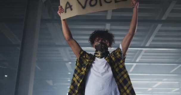 Змішаний Гоночний Чоловік Масці Обличчя Тримає Плакат Протесту Порожньому Гаражі — стокове відео