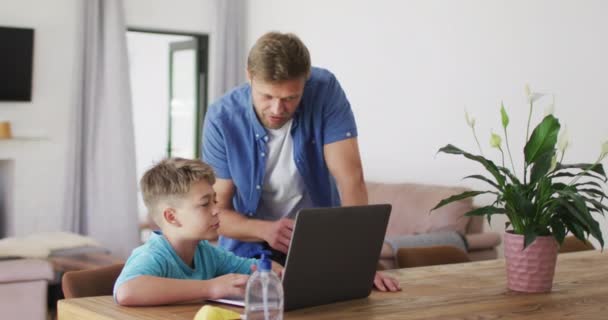 Caucasian Man Standing Helping His Son Sitting Table Using Laptop — Stock Video