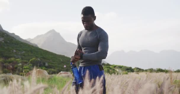 Afrykański Amerykanin Pijący Wodę Podczas Ćwiczeń Wsi Sprawdzający Zegarek Fitness — Wideo stockowe