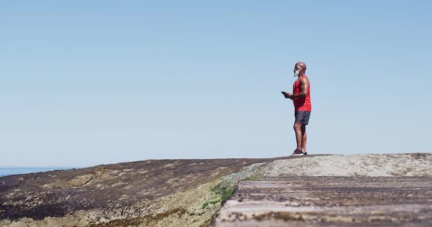 Homme Afro Américain Senior Faisant Exercice Utilisant Smartphone Sur Des — Video