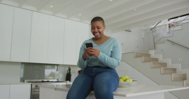 Счастливый Африканский Американец Плюс Размер Женщина Сидит Столешнице Кухне Используя — стоковое видео
