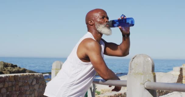 Homem Afro Americano Sênior Exercitando Água Potável Rochas Beira Mar — Vídeo de Stock