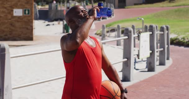 Pria Afrika Amerika Senior Dengan Air Minum Basket Lapangan Dekat — Stok Video