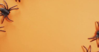 Turuncu arka planda fotokopi alanı olan birden fazla örümcek oyuncağını kapatın. Cadılar Bayramı bayramı ve kutlama konsepti