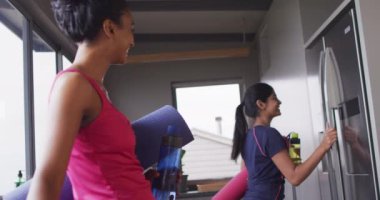 Yoga yapmaya hazırlanan mutlu çift ırklı kız arkadaşlarının videosu. Arkadaşlık, evde birlikte zaman geçirmek..