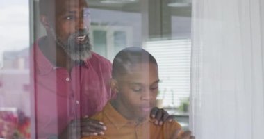 Afro-Amerikan bir babanın pencerede dikilip oğlunu teselli ettiği bir video. Ebeveynlik, ayaklanma ve aile zaman kavramı.