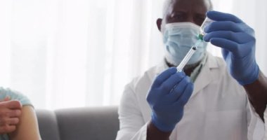 Yüz maskesi takan erkek Afrikalı Amerikalı doktor şırıngaya kovid 19 aşısı yerleştiriyor. Salgın sırasında korona virüsü tedavisi ve aşı kavramı.