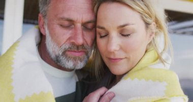 Battaniyeye sarılı mutlu beyaz bir çift. Sahildeki evdeki boş vakitlerin tadını çıkarıyorum.