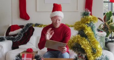 Mutlu albino Afrikalı Amerikalı adam Noel Baba şapkası takıyor ve Noel 'de video görüşmesi yapıyor. Noel, şenlik ve iletişim teknolojisi.