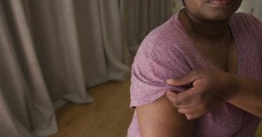 Kolunda alçı olan Afrikalı Amerikalı bir kadın Coronavirus aşısı olduğu yeri gösteriyor. covid 19 salgını sırasında sağlık ve yaşam tarzı.