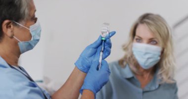 Kıdemli Afro-Amerikan kadın doktor yüz maskesi takan kadın için aşı hazırlıyor. Coronavirus covid 19 salgını sırasında sağlık, hijyen ve koruma.