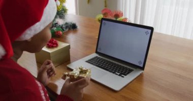Mutlu Afro-Amerikan artı Noel Baba şapkalı cüsseli kadın, Noel 'de dizüstü bilgisayarla video görüşmesi yapıyor. Noel, kış, gelenek ve evde kutlama.