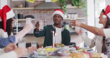 Noel Baba şapkalı çeşitli arkadaşlar yemeği kutluyor, Noel zamanı meyve suyuyla kadeh kaldırıyor. Yılbaşı kutlamaları, evde arkadaşlarla kutlama..
