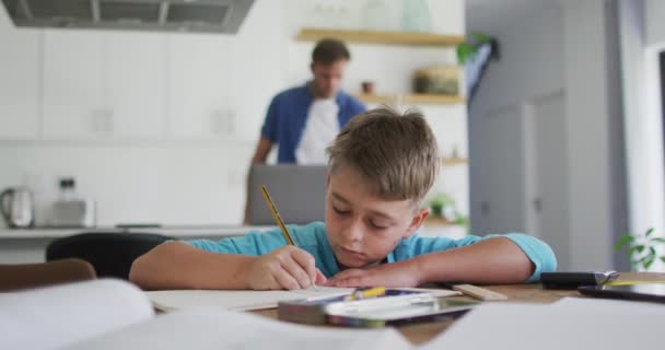 Beyaz Çocuk Evde Ödevlerini Yaparken Babam Arka Planda Dizüstü Bilgisayar — Stok video