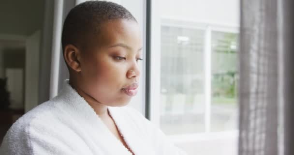 Nachdenkliche Afrikanisch Amerikanische Size Frau Robe Die Durch Das Fenster — Stockvideo
