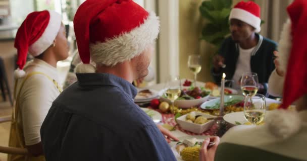 クリスマスの時間に友人と食事を祝うサンタ帽子の幸せな白人男性 クリスマスのお祝い友達と家でお祝いする — ストック動画