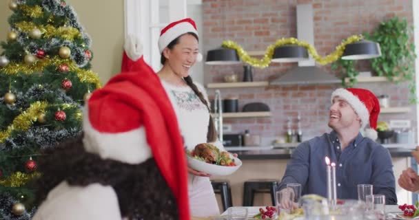 Χαρούμενη Ομάδα Διαφορετικών Φίλων Καπέλα Σάντα Γιορτάζουν Γεύμα Τους Χριστούγεννα — Αρχείο Βίντεο