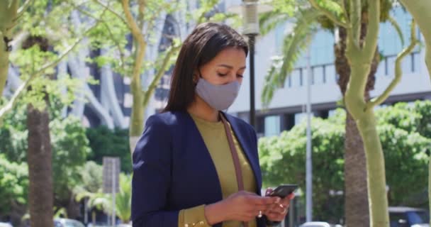 戴口罩的非裔美国女人在街上用智能手机 科罗纳韦病毒 Coronavirus Covid 大流行期间 — 图库视频影像
