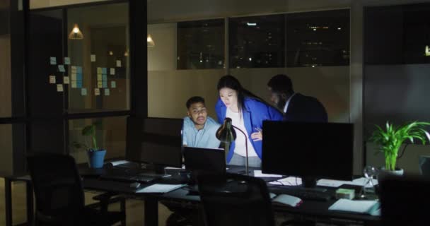 オフィスで夜に話すコンピュータを使用して3人の幸せな多様な男性と女性の同僚のビデオ ビジネス コミュニケーション 包括性 柔軟な作業コンセプトデジタルで生成されたビデオ — ストック動画