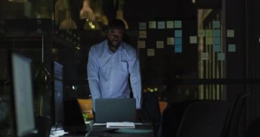 Geç saatlere kadar çalışan yorgun Afro-Amerikan iş adamının gece bilgisayar ve ofis masasından ayrılışının videosu. İş, iletişim, kapsayıcılık ve dijital olarak oluşturulan esnek çalışma konsepti.