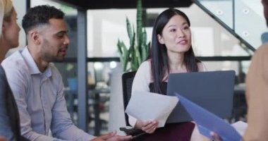 Asyalı iş kadınının ofis toplantısındaki çeşitli iş arkadaşlarıyla konuştuğu bir video. İş, iletişim, kapsayıcılık ve dijital olarak oluşturulan esnek çalışma konsepti.