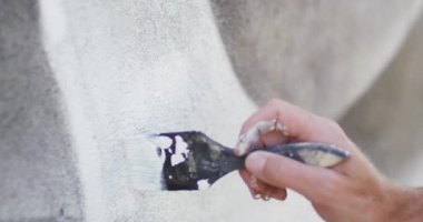 Beyaz boya ve fırça kullanarak duvara duvar resmi yapan beyaz erkek ressamın el videosu. Özgürlük, yaratıcılık, sanat ve hobiler dijital olarak üretilen video konsepti.