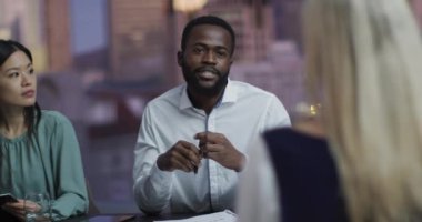 Afrika kökenli Amerikalı iş adamının akşam ofis toplantısında çeşitli meslektaşlarıyla konuştuğu bir video. İş, iletişim, kapsayıcılık ve dijital olarak oluşturulan esnek çalışma konsepti.