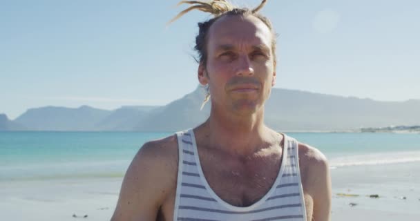 照片上站在阳光明媚的海滩上 一个有着可怕头发的白人微笑男子 福祉和健康生活方式概念数码视频 — 图库视频影像