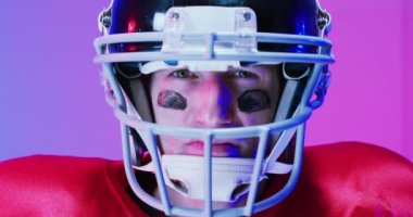 Kafkaslı beyaz amerikalı futbolcunun portresi, neon mor arka planda. Amerikan futbolu, spor ve yarışma konsepti.