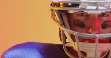 Kafkaslı beyaz amerikalı futbolcunun neon sarısı arka planda yakın çekim videosu. Amerikan futbolu, spor ve yarışma konsepti.