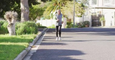 Sunny Caddesi 'nde spor kıyafetleri ve kulaklıklar takmış yaşlı bir adamın videosu. Emeklilik, hobiler, sağlık, kapsayıcılık ve aktif kıdemli yaşam tarzı konsepti.